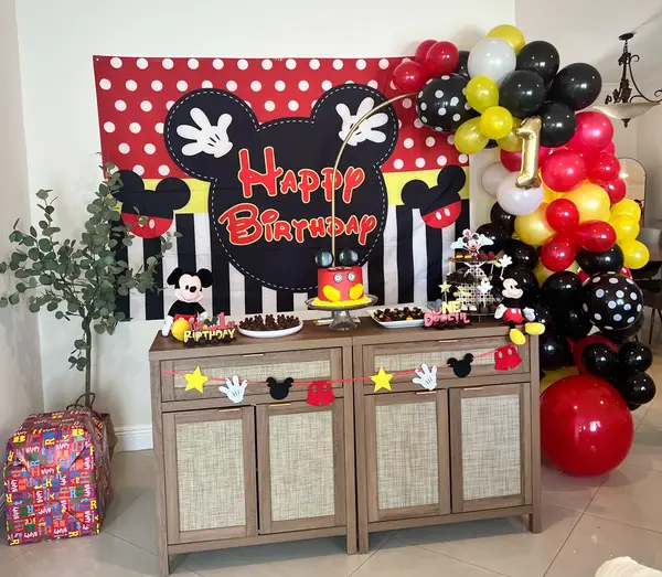 Mickey Mouse first birthday party setup with red and black balloon garland and themed dessert table in South Florida